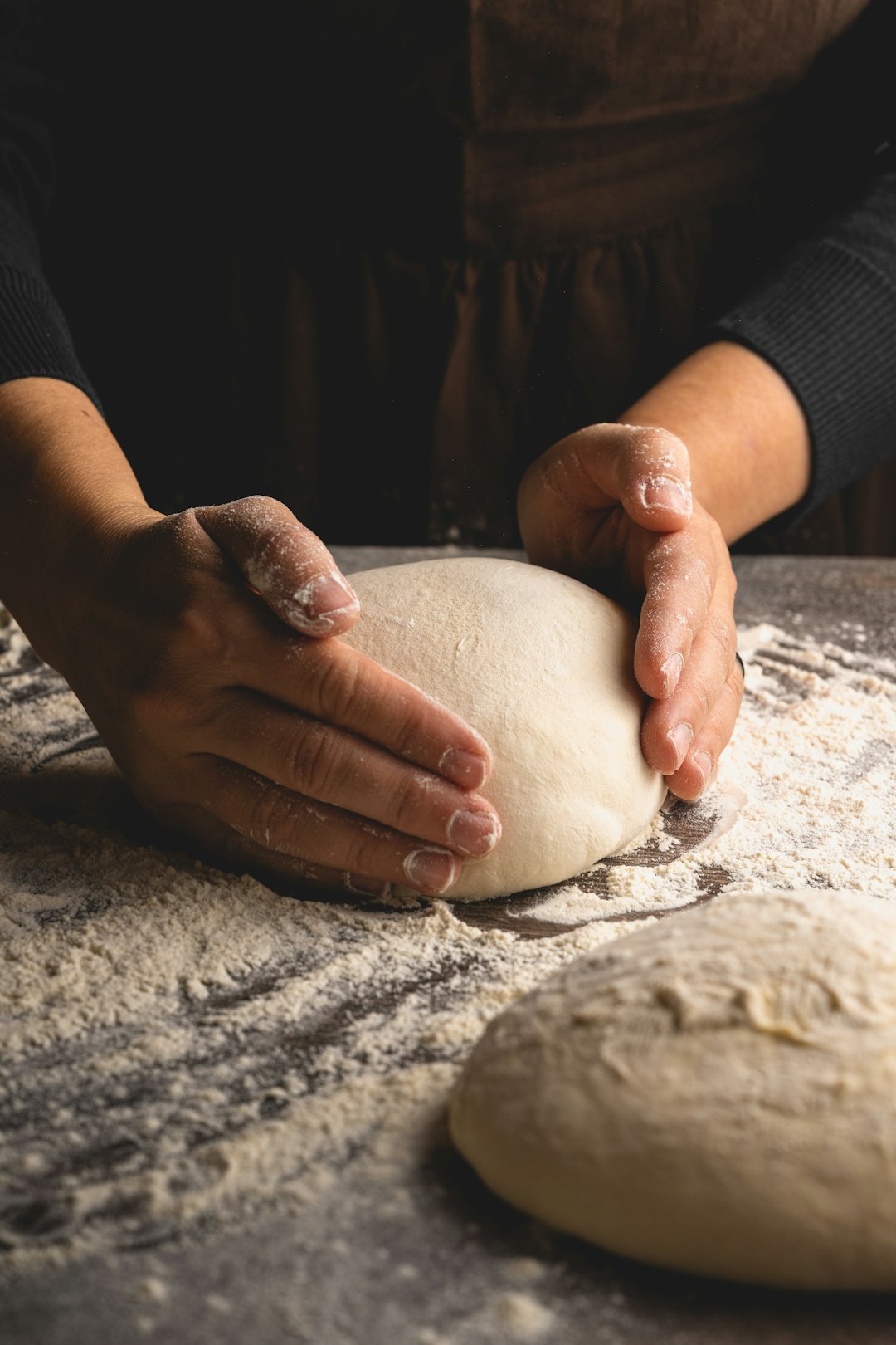 Manos formando una bola de masa sobre harina