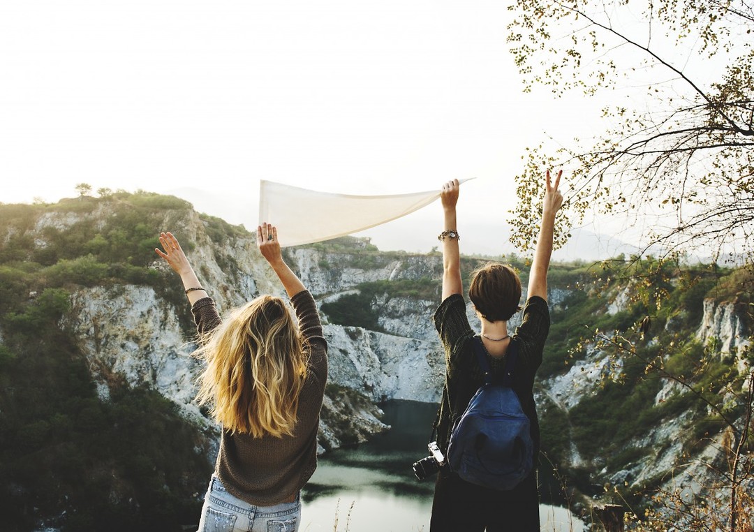 Two women travelers celebrating on a cliff