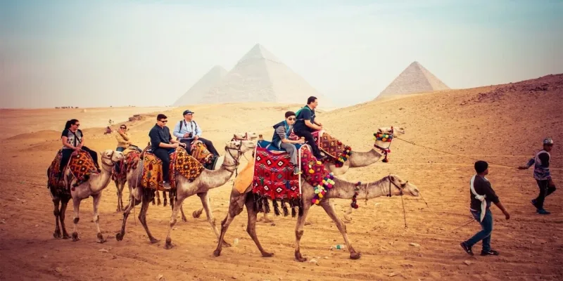 Travelers on camelback before the Pyramids of Giza