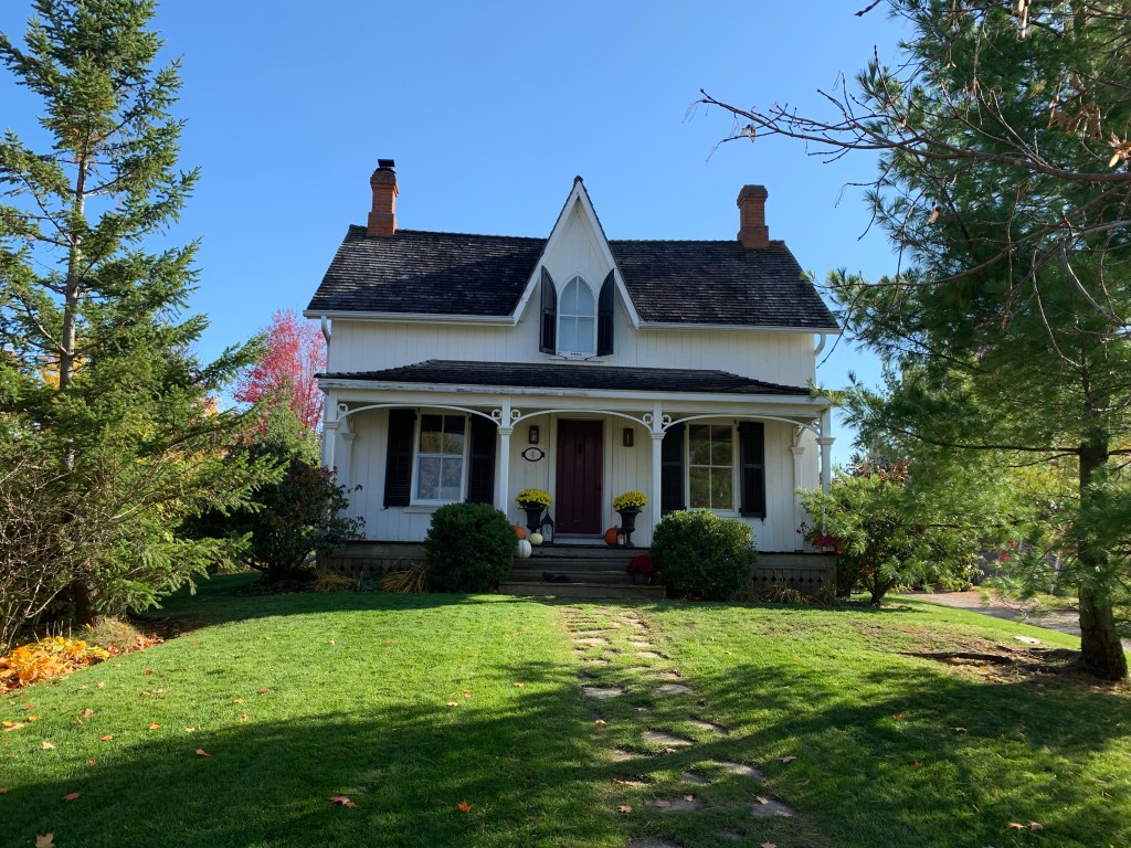 White heritage farmhouse with black shutters in Markham Heritage Estates near Brown's Corners
