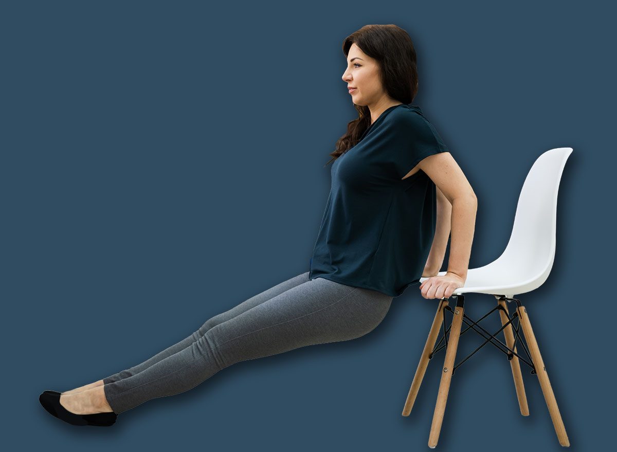 Woman performing triceps dips using a sturdy chair with legs extended forward