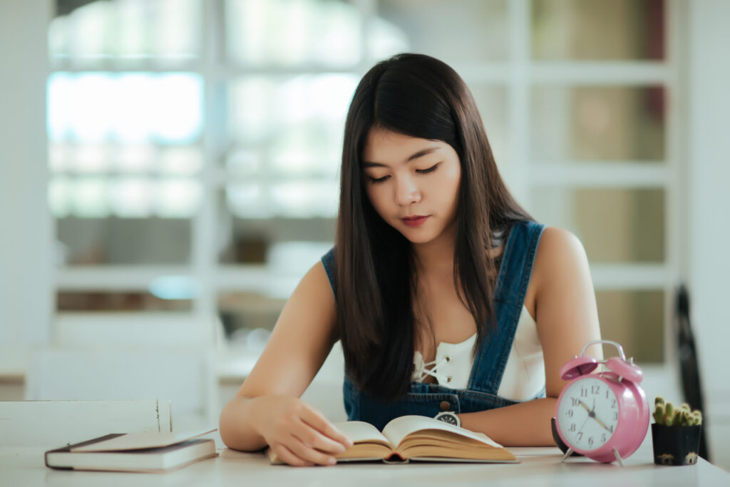 Focused student studying at desk with alarm clock showing disciplined concentration