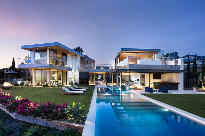 Completed contemporary residence at dusk, glass walls glowing beside a reflecting pool