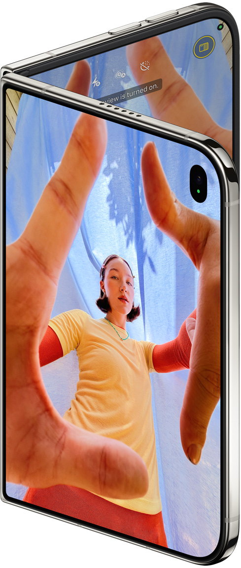 iPhone Duo pose setengah terbuka dengan antarmuka kamera dan subjek membentuk frame dengan tangan