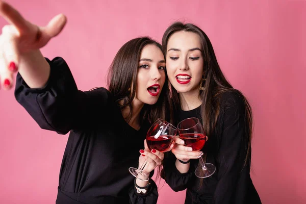 Dos mujeres brindando con vino tinto y sonriendo durante una fiesta de fin de año.