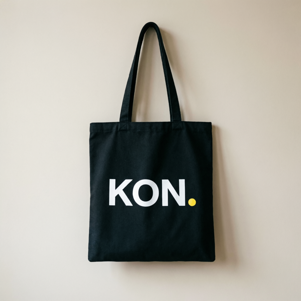 Signature Tote — black canvas tote with KON. print