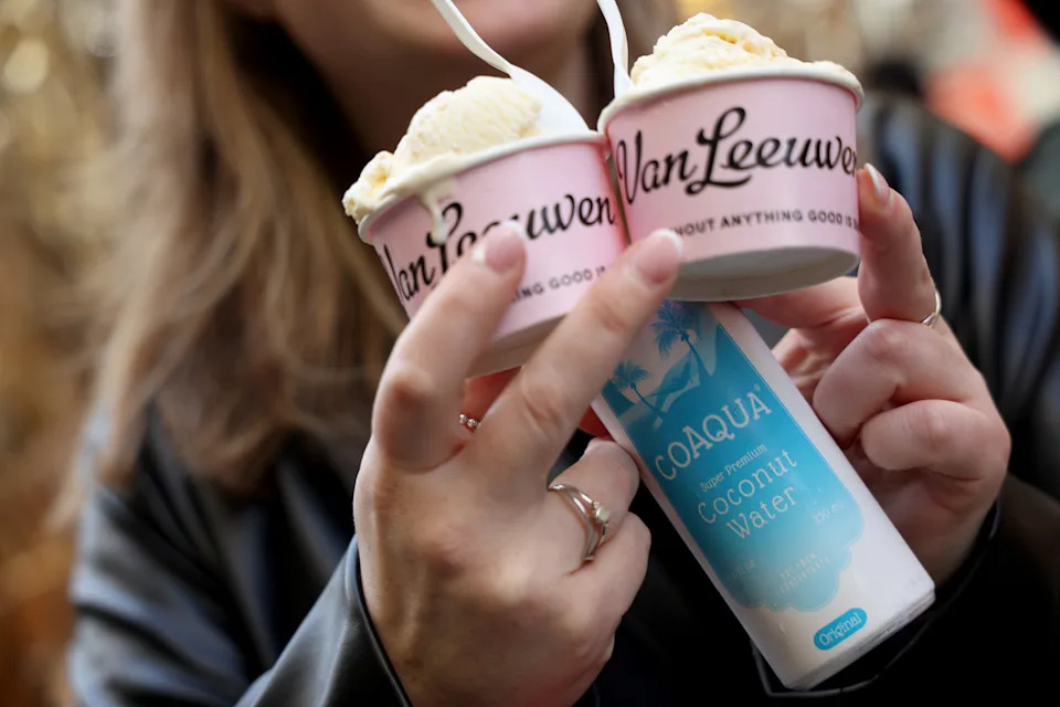 Two pink Van Leeuwen ice cream cups with the brand's black script logo held by a customer
