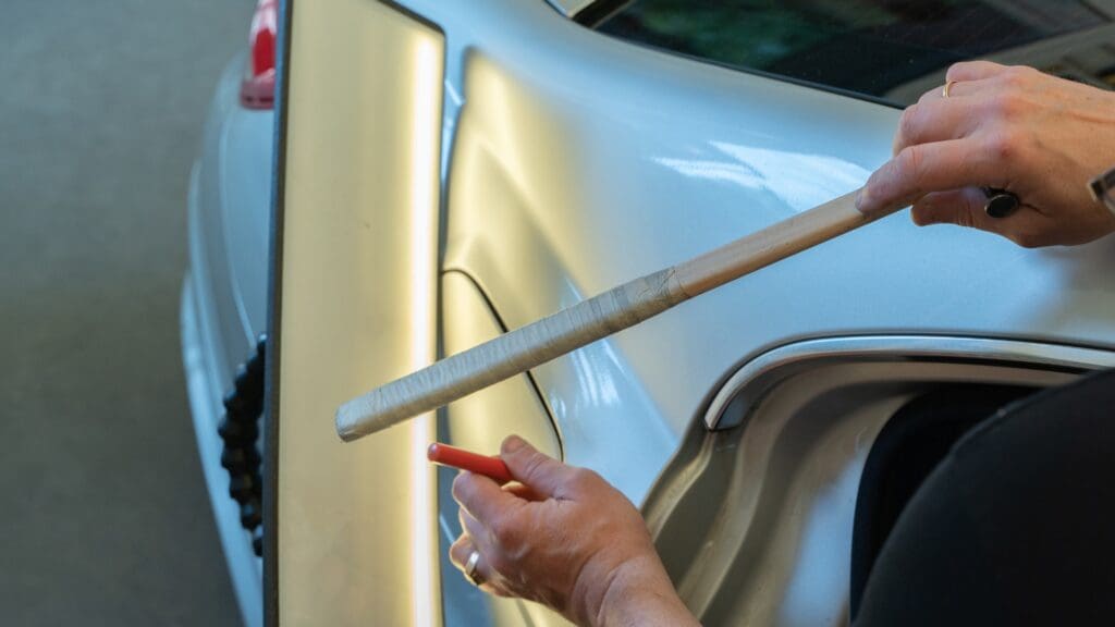 Paintless dent repair technician working on car panel