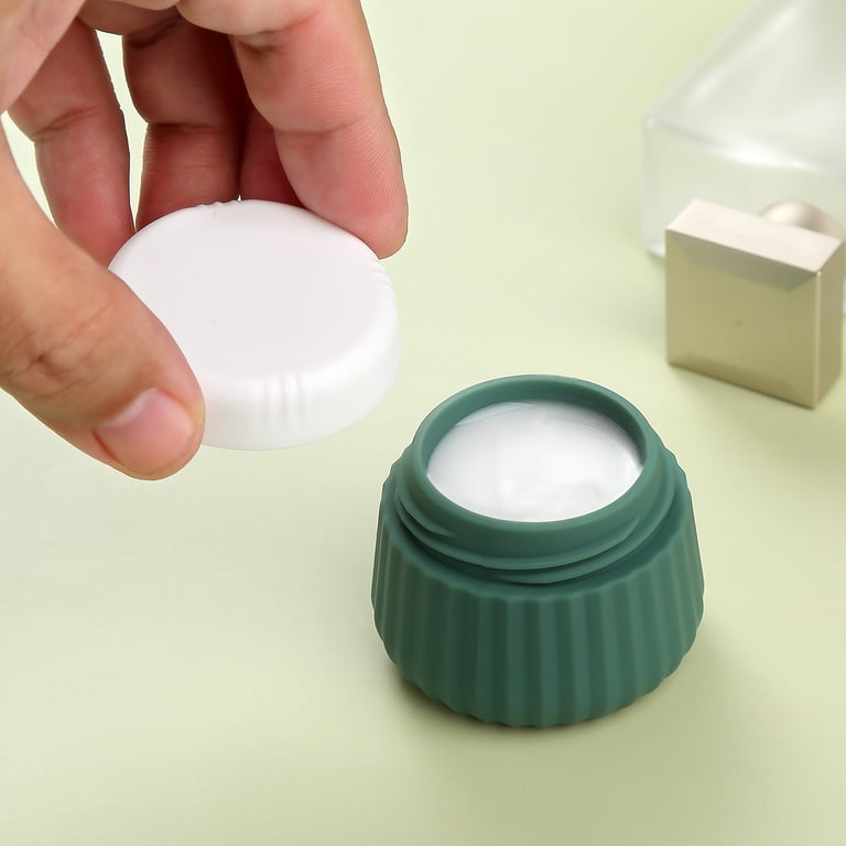 A hand opening a tiny travel jar of cream