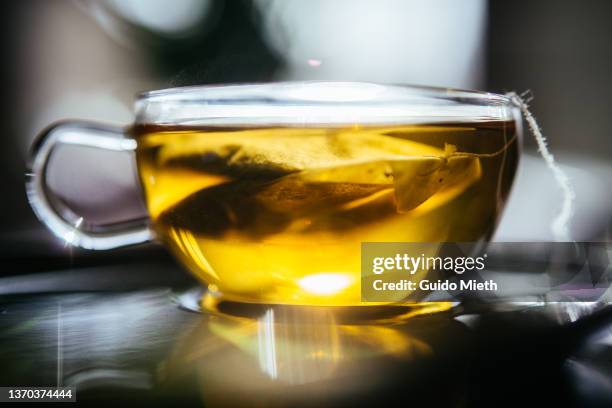 A glass cup of golden herbal tea glowing in dim light