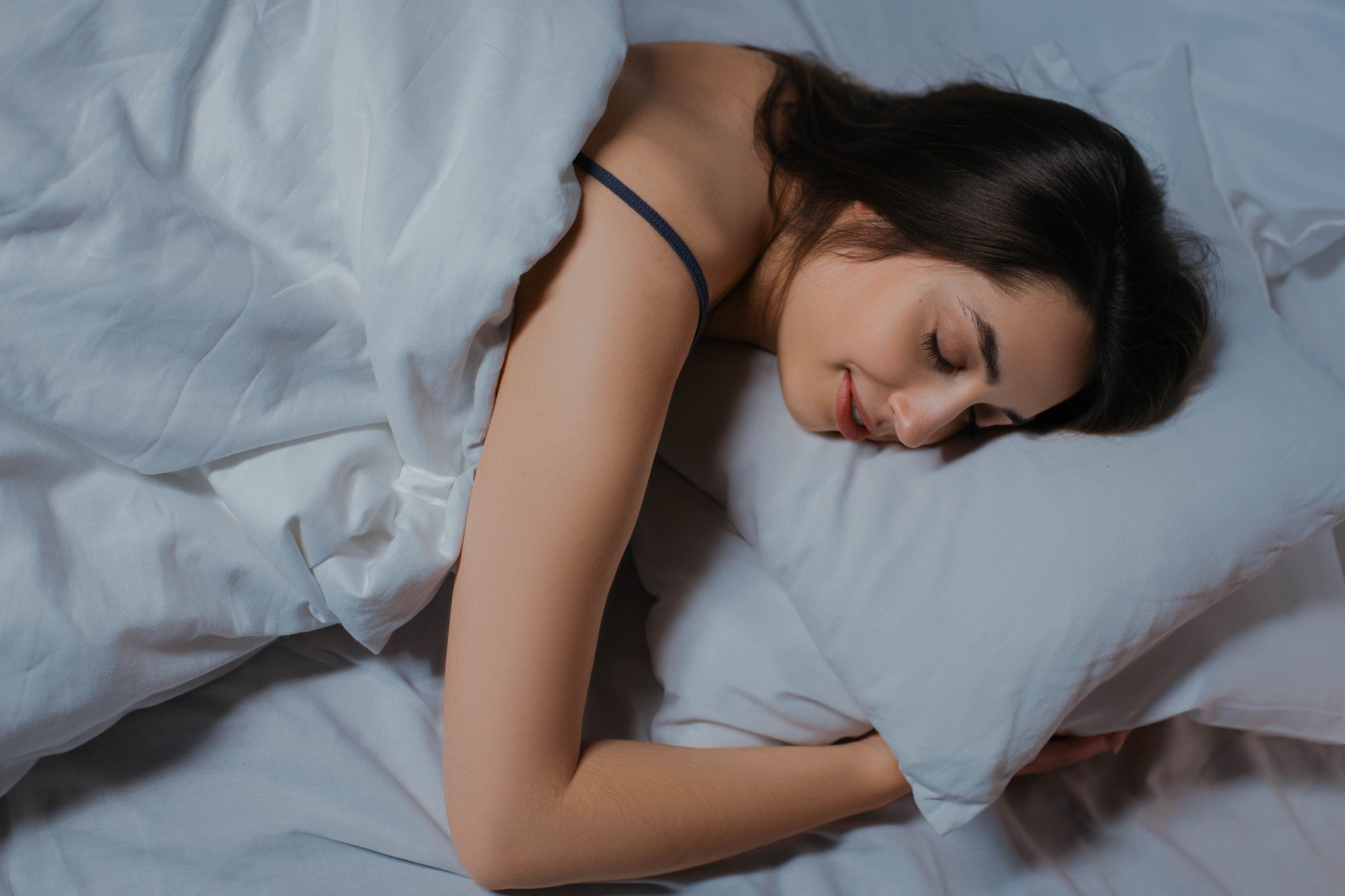 A woman sleeping peacefully under soft white bedding