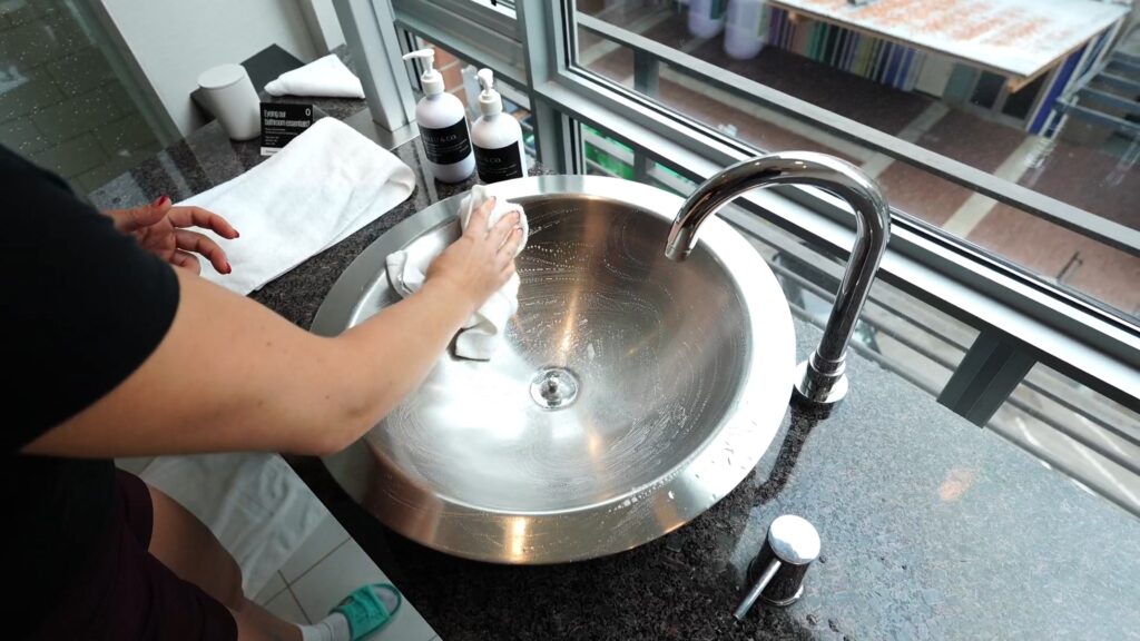 A traveler hand-washing clothes in a hotel sink