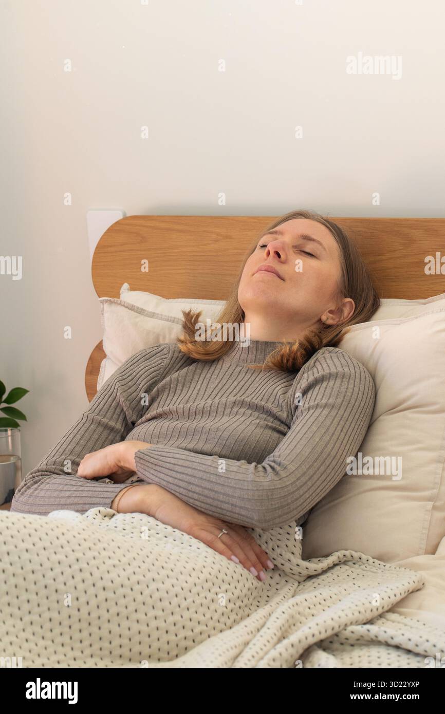 A woman lying back on a bed with eyes closed, deeply relaxed
