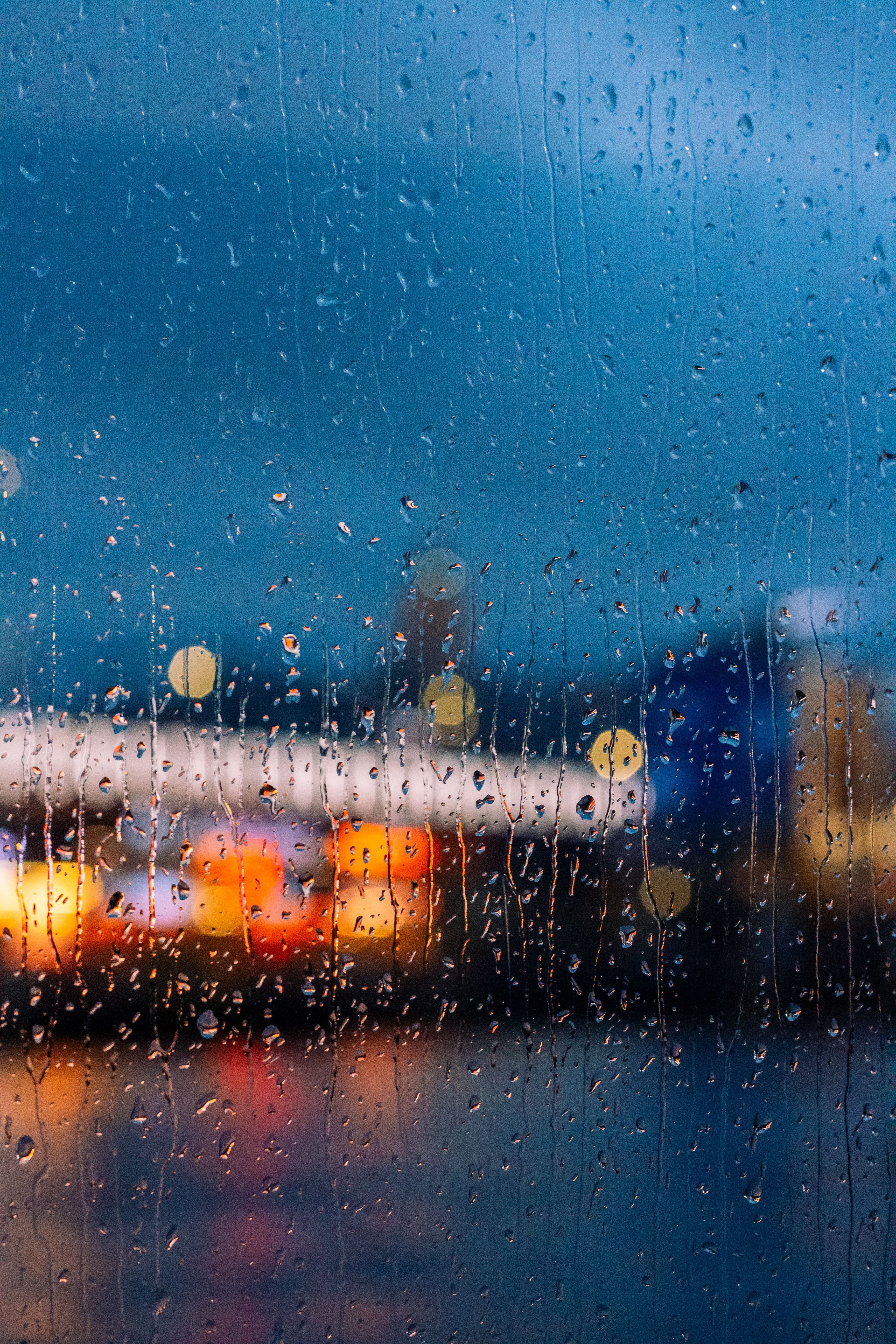 Rain droplets on a window with blurred city lights at night