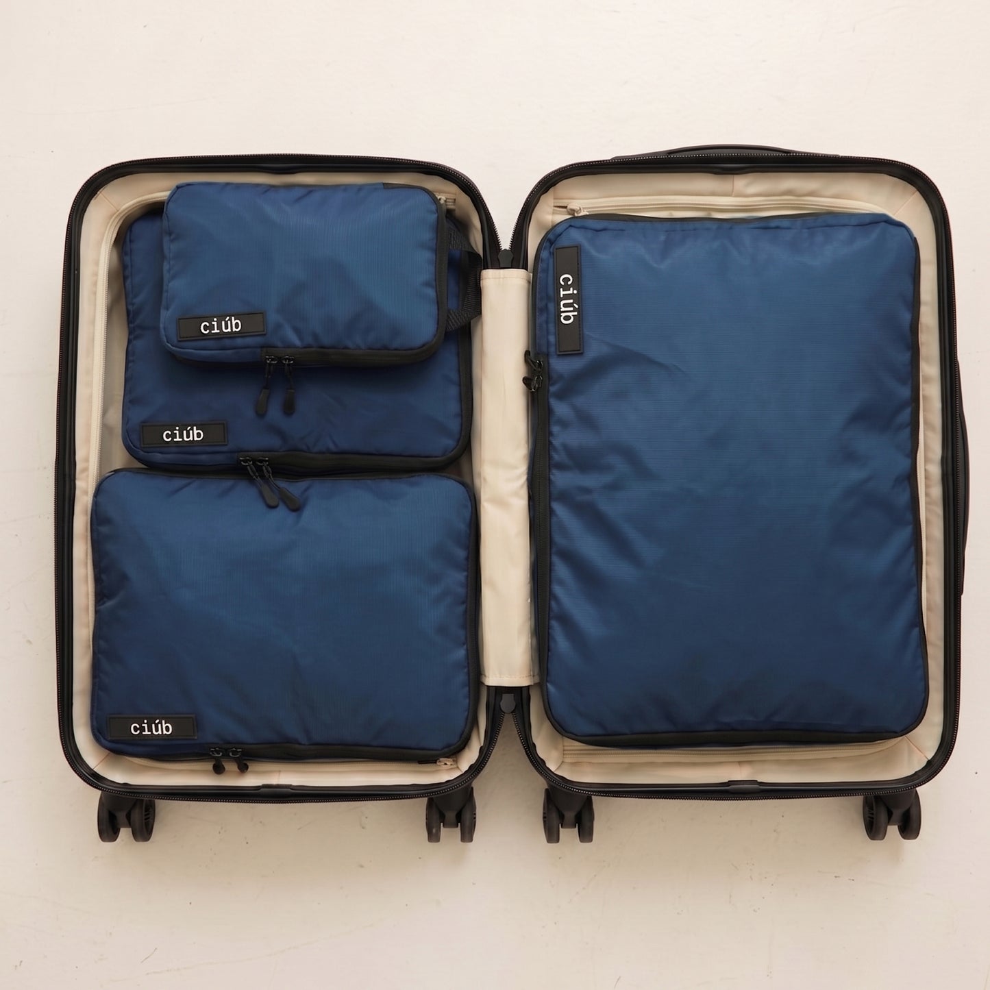 An open carry-on suitcase perfectly organized with navy packing cubes