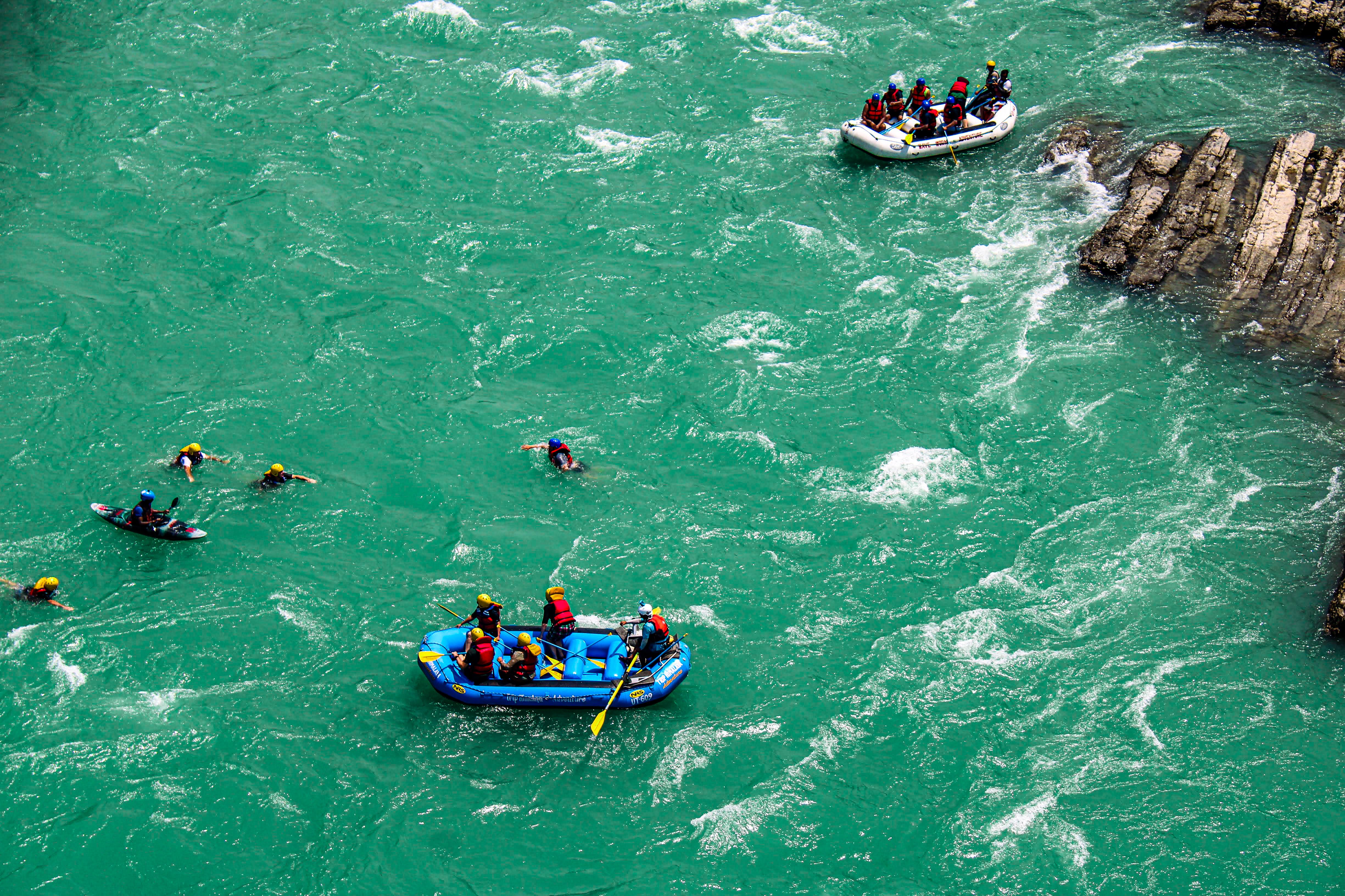 Rafters swimming beside a raft wearing certified life jackets during a Bali rafting tour