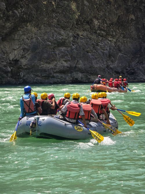 White water rafting boat paddling through a green jungle gorge in Bali