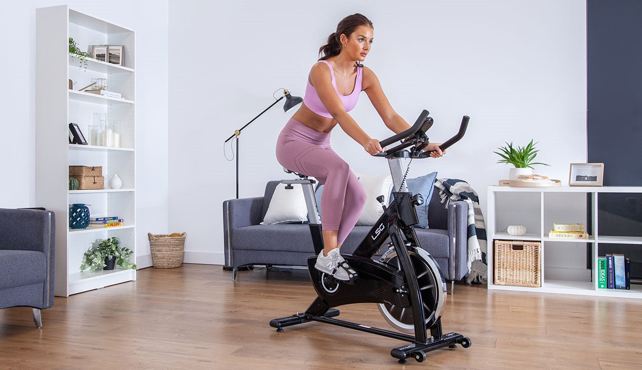 Mulher treinando em bicicleta ergométrica em casa