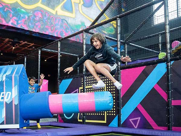 Kid jumping on trampoline into foam zone