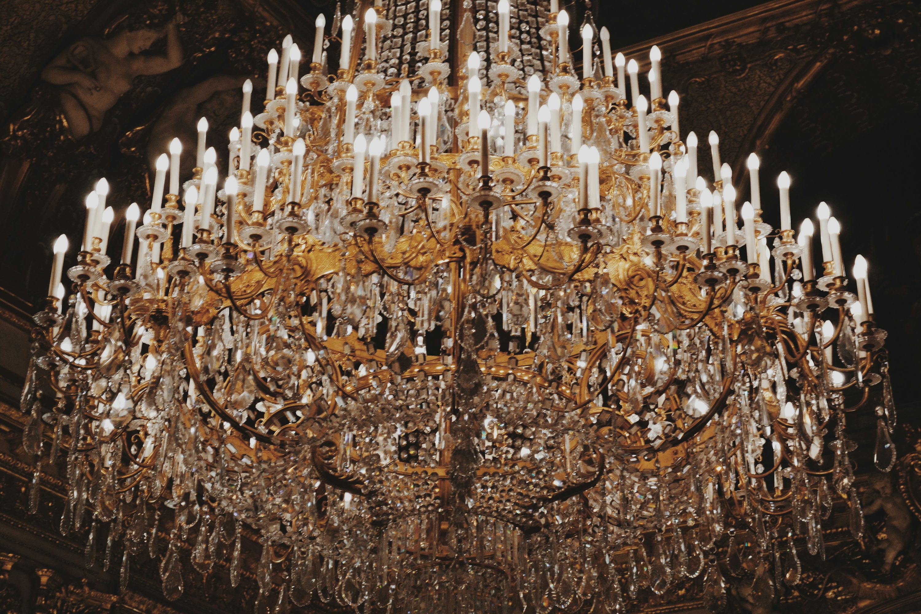 Golden crystal chandelier glowing in the dark — premium lighting