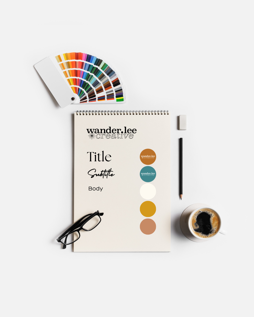 Typography specimen sheet with brand color palette and swatch fan on a designer desk