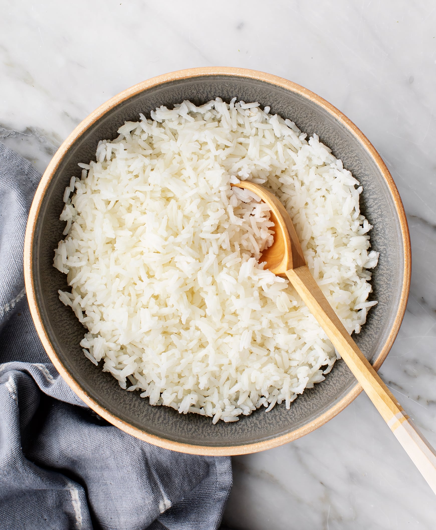 Perfect fluffy white rice in bowl with wooden spoon